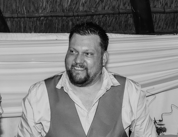 Shaun, dressed smartly, sitting at a table and smiling